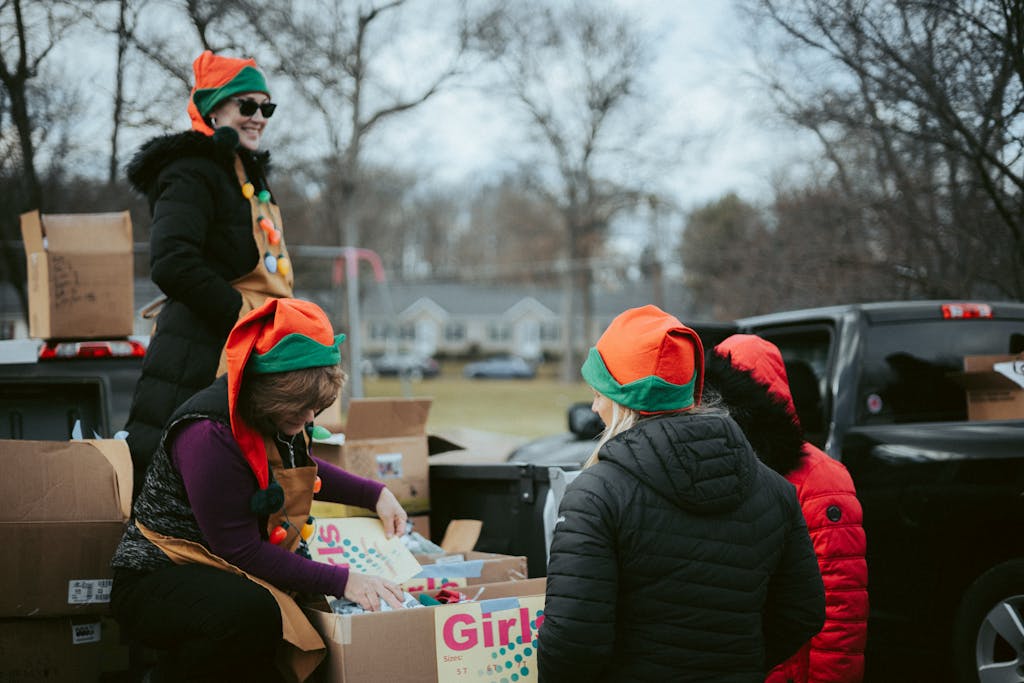 A group of volunteers in festive attire distributing Christmas gifts from truck.