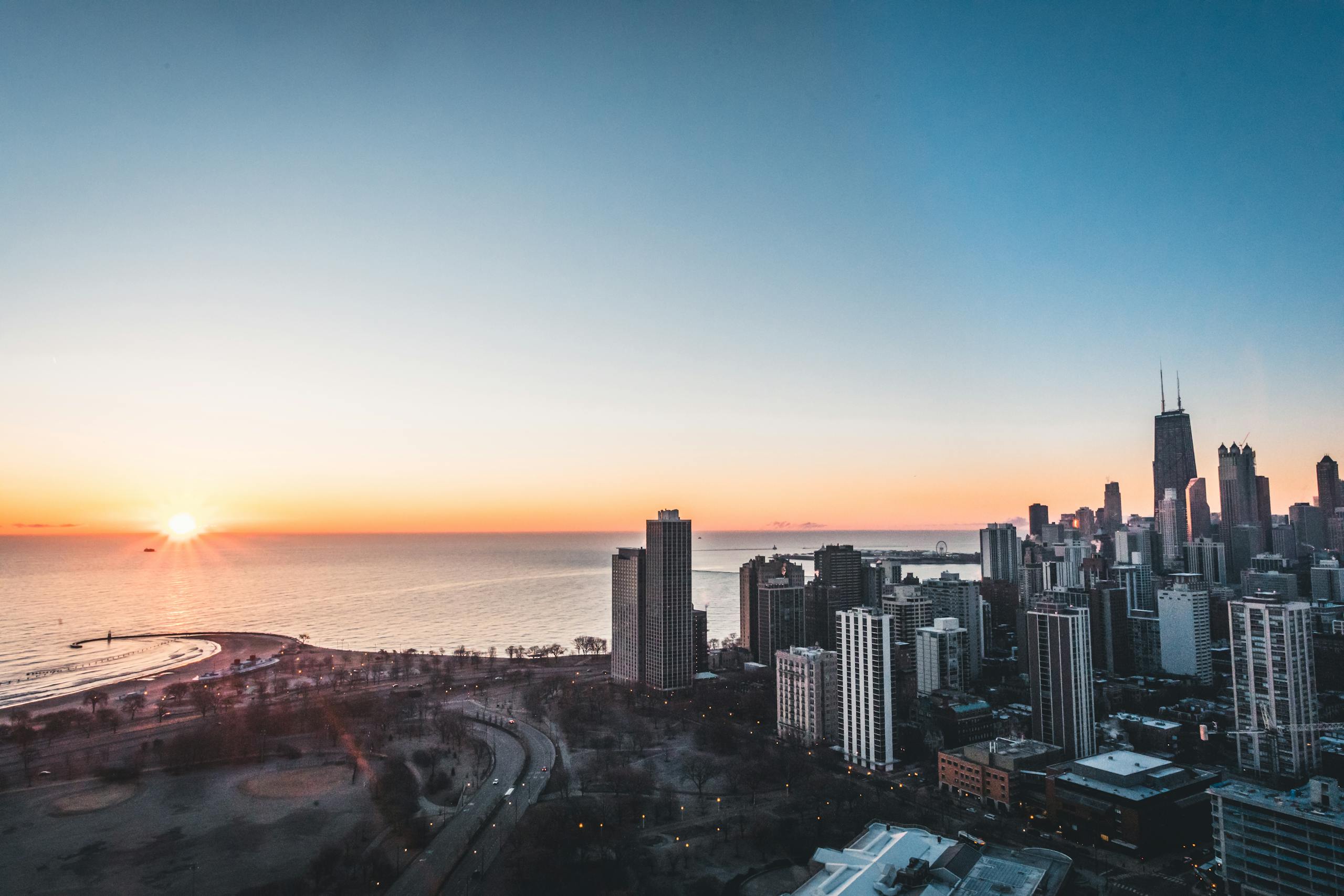 A breathtaking aerial view of the Chicago skyline at sunrise with Lake Michigan prominently featured.